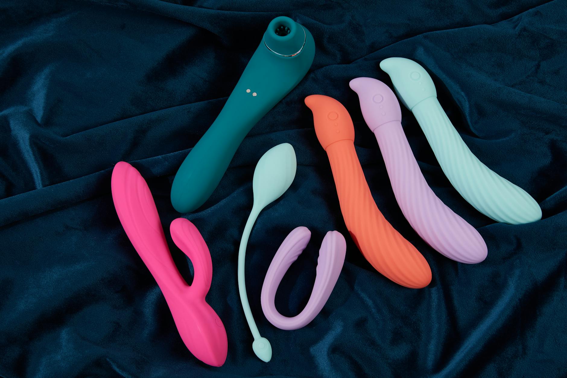 Silicone vibrators arranged on dark fabric, showing varied texture and color options