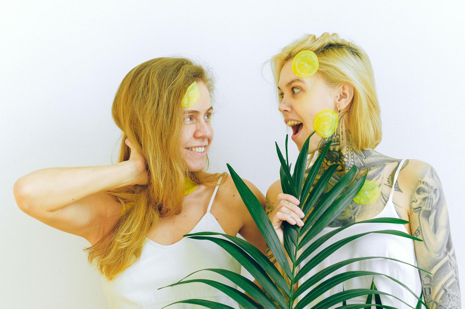 Two women smiling together with tropical plants, expressing joy and comfort indoors