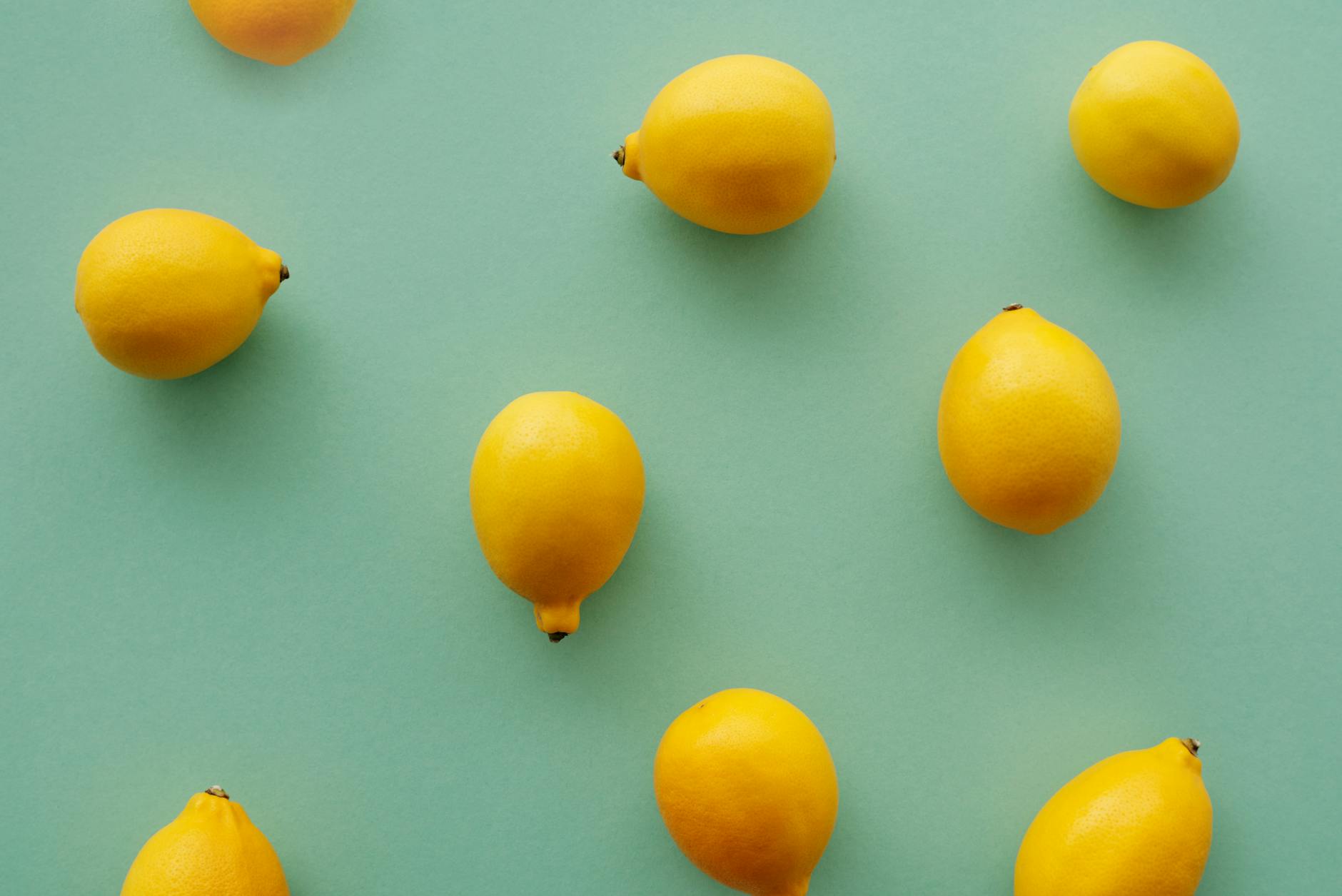 Bright yellow lemons arranged on a pastel green background symbolizing fresh sensation and renewed pleasure