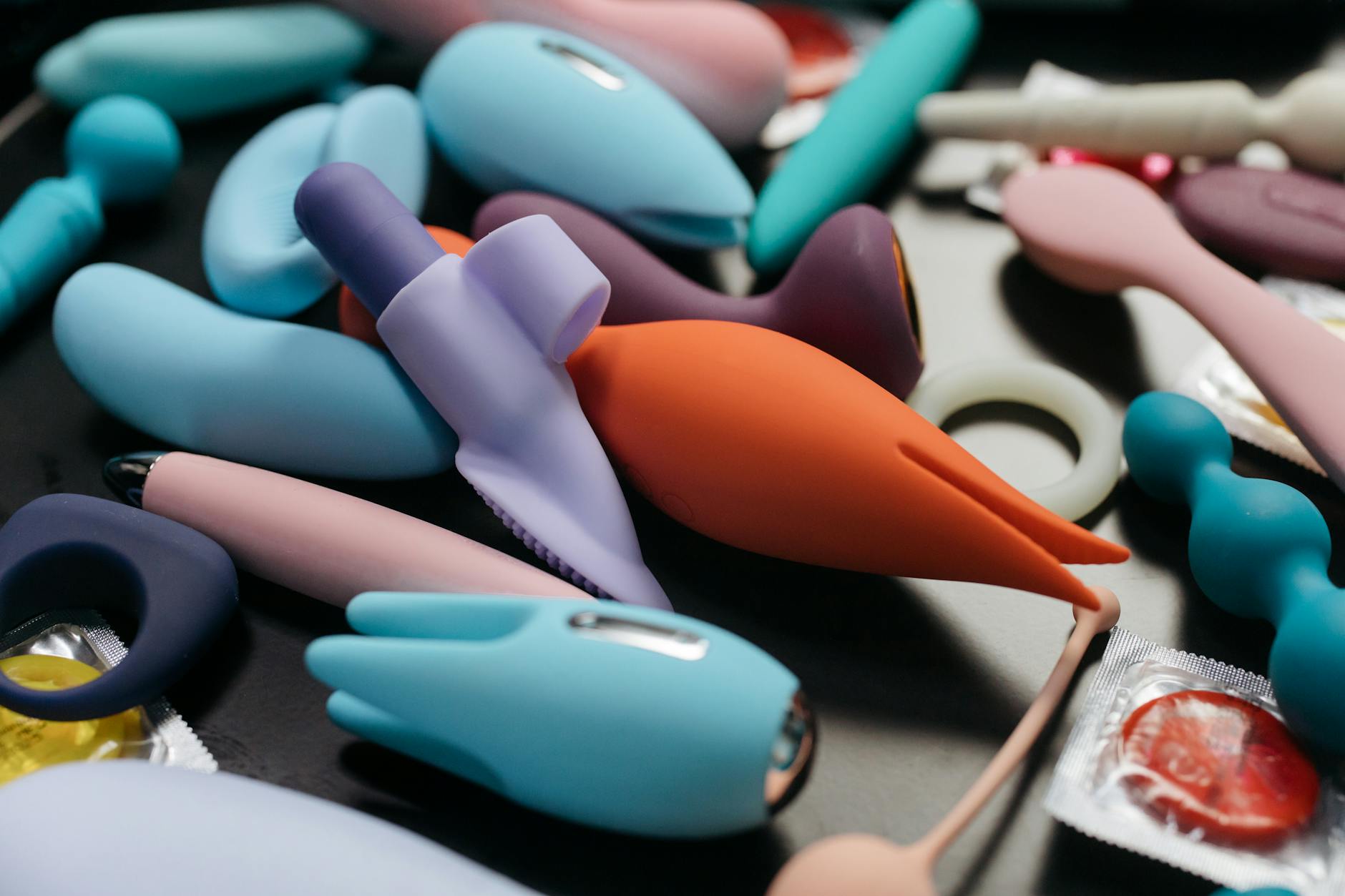 A vibrant collection of various clitoral vibrators and pleasure devices on a dark surface