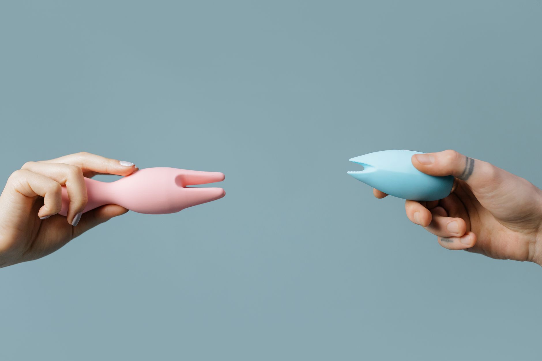 Two hands holding vibrators against a pastel background, symbolizing intimate reconnection