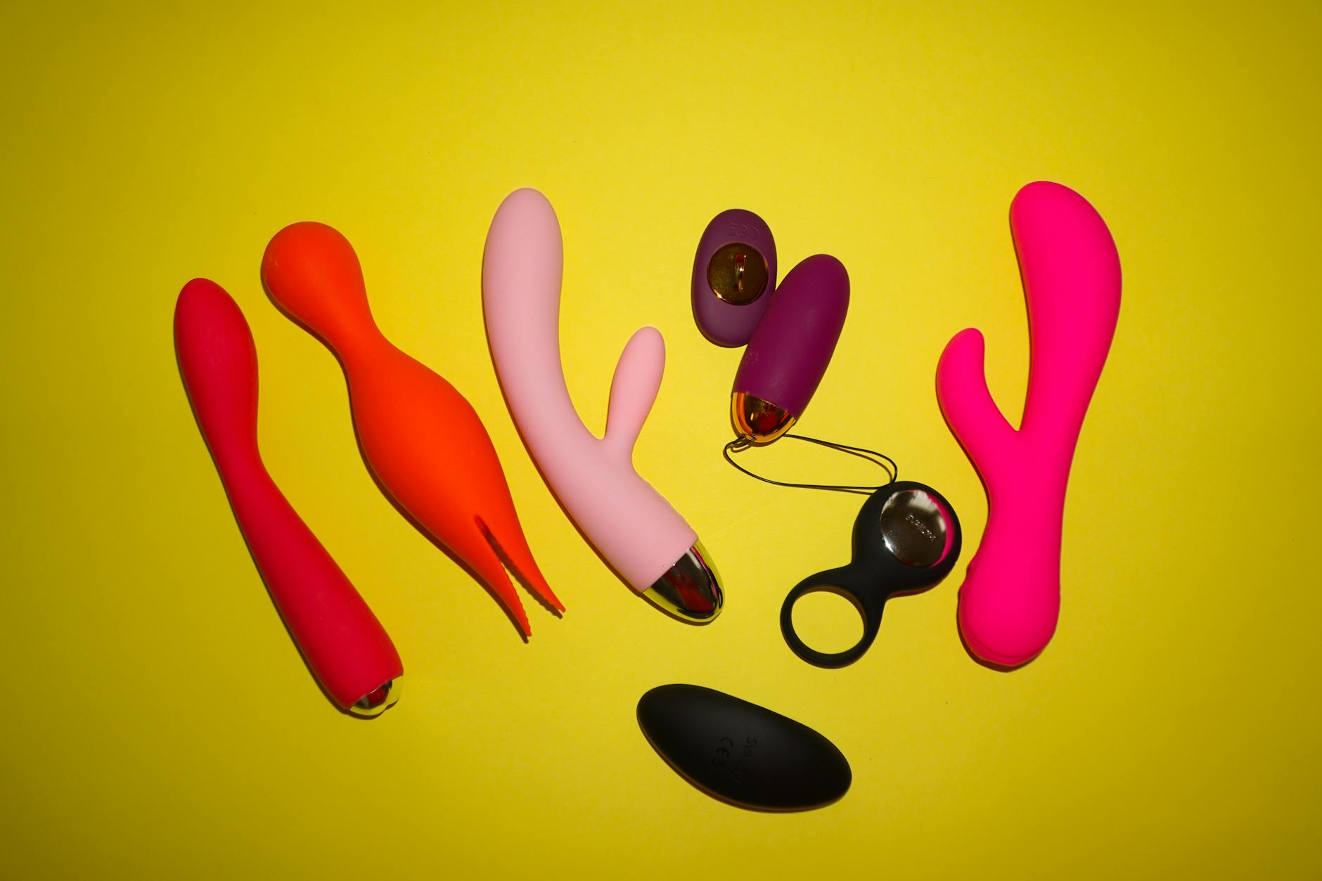 Colorful vibrators arranged on a bright yellow background, showcasing various designs and shapes.