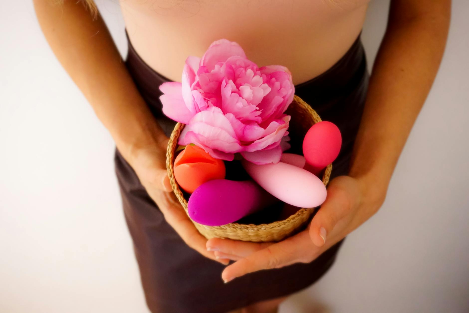 Woman holding blue and pink clitoral vibrators in a thoughtful moment